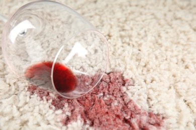 Photo of Overturned glass and spilled exquisite red wine on soft carpet, closeup. Space for text