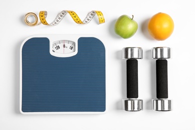 Photo of Composition with scales, fruits, tape measure and dumbbells on white background, top view
