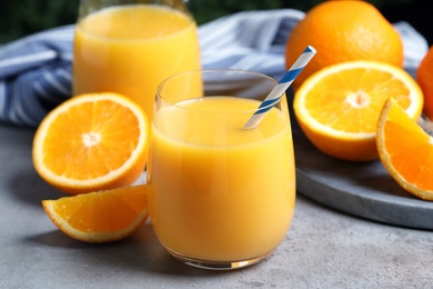 Glass of orange juice and fresh fruits on grey table, closeup