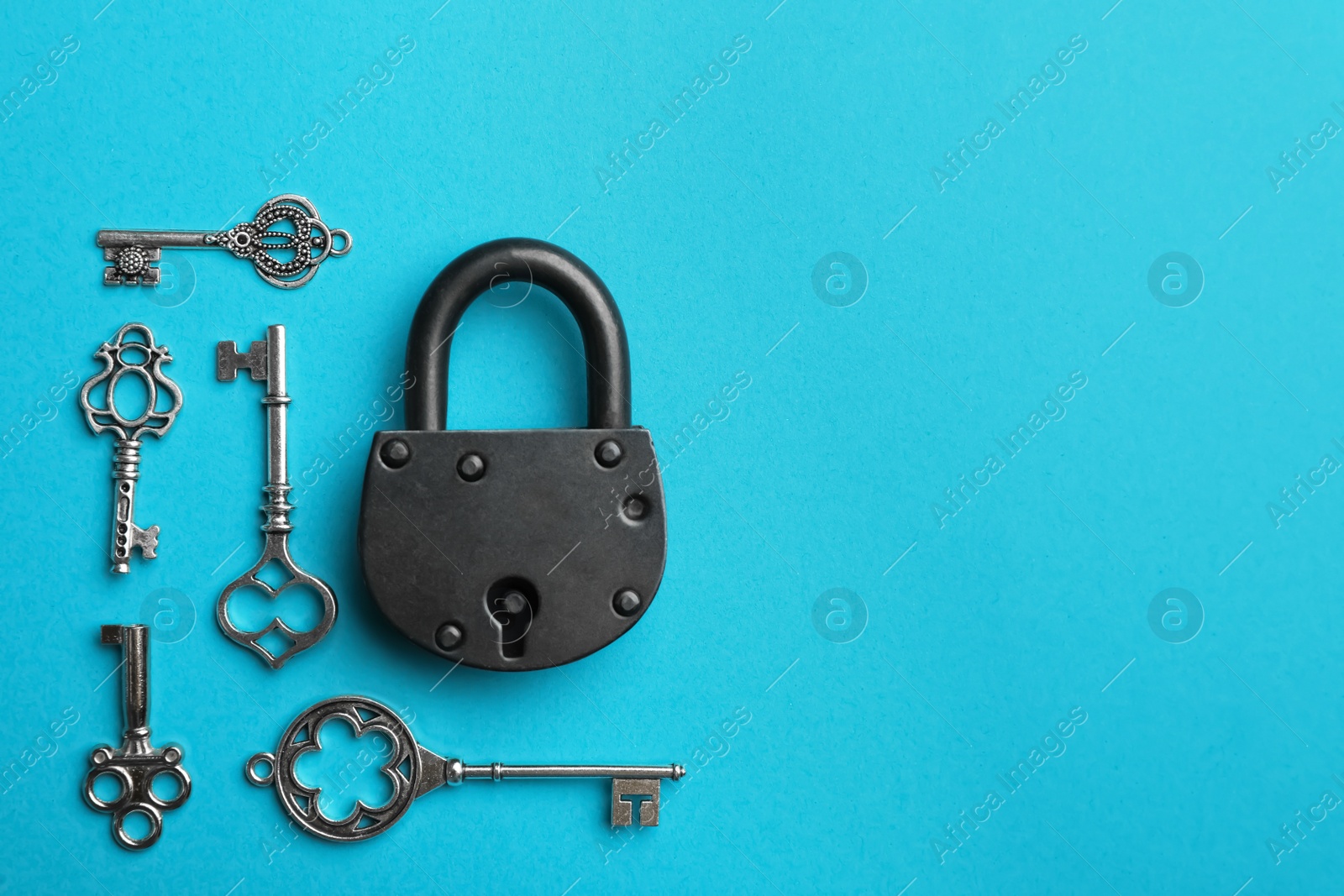 Photo of Padlock and beautiful vintage keys on light blue background, flat lay. Space for text