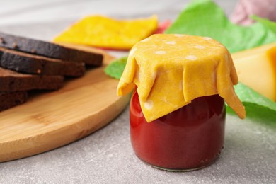 Photo of Jar of tomato paste covered with beeswax food wrap on light grey table