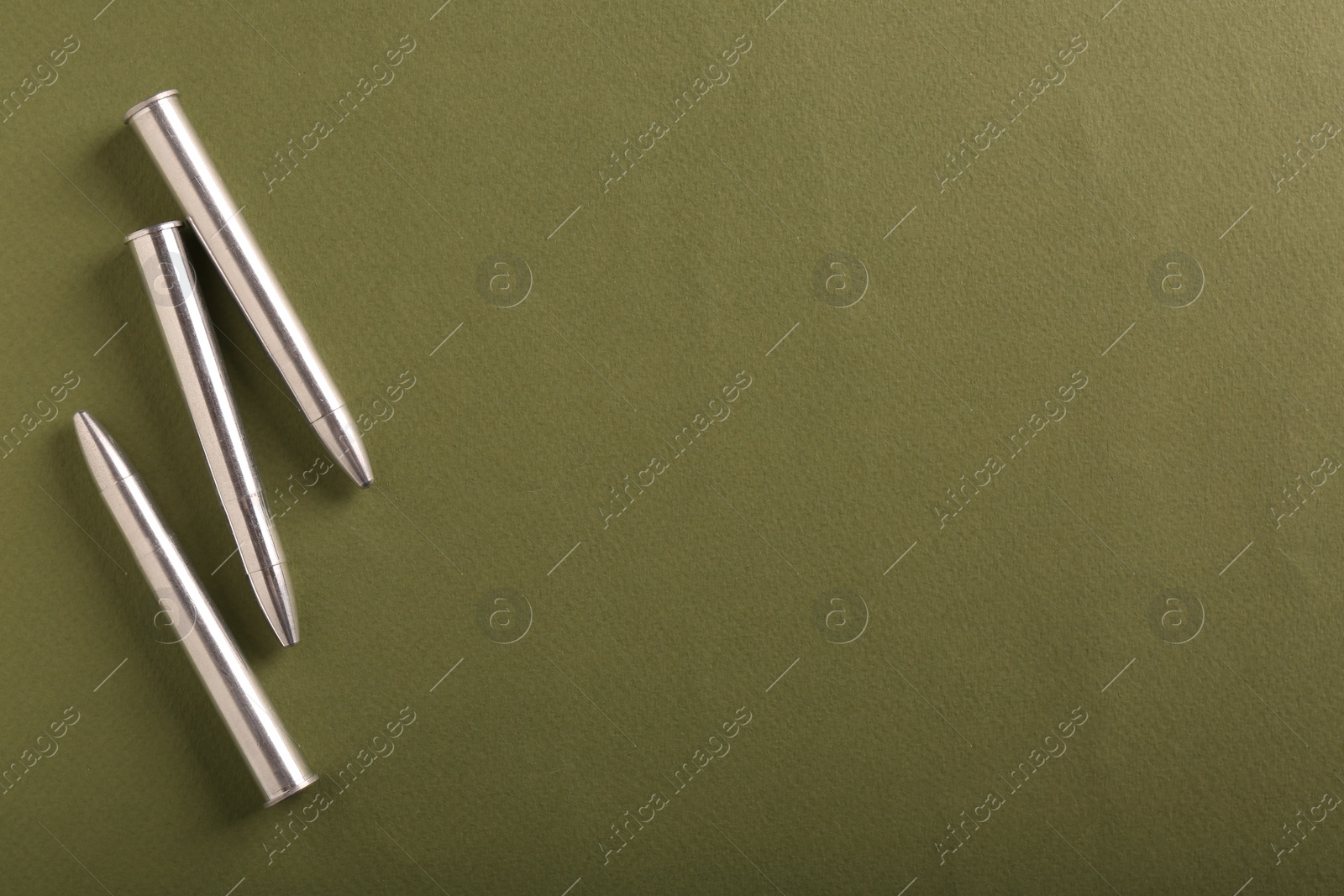 Photo of Many metal bullets on green background, flat lay. Space for text