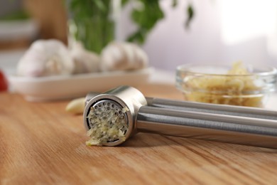 Garlic press with mince on wooden table indoors, closeup