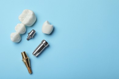 Photo of Parts of dental implant and bridge on light blue background, flat lay. Space for text