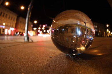Photo of Crystal ball on asphalt road at night, space for text. Wide-angle lens