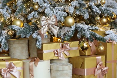 Photo of Many gift boxes under decorated Christmas tree at home, closeup