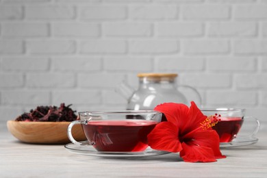 Photo of Delicious hibiscus tea and beautiful flower on light wooden table, space for text