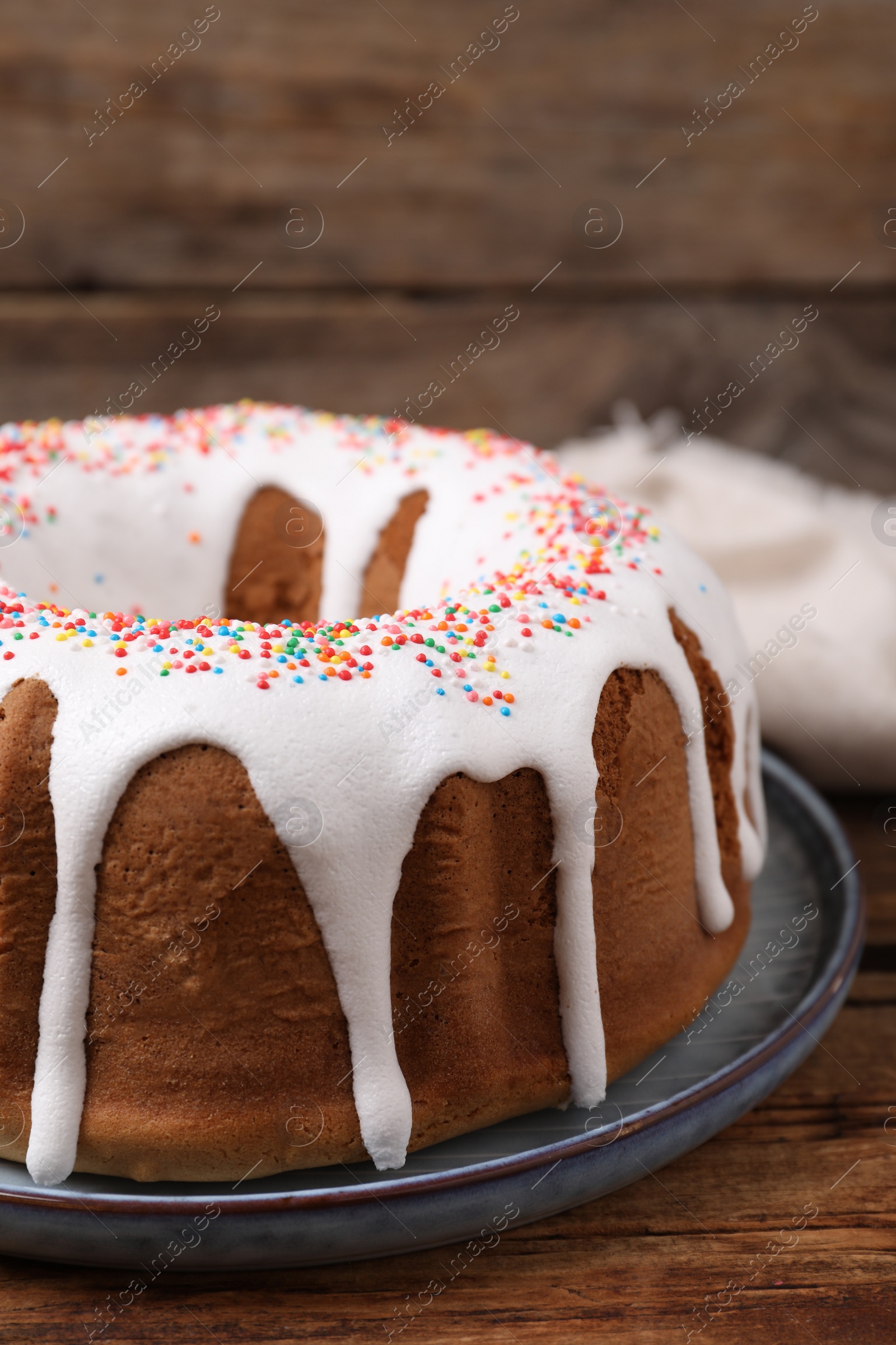 Photo of Glazed Easter cake with sprinkles on wooden table, closeup