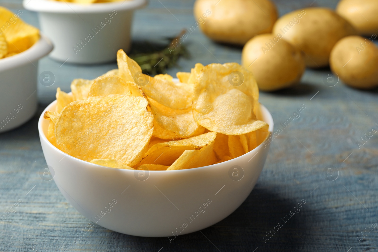 Photo of Bowl of crispy potato chips on wooden table