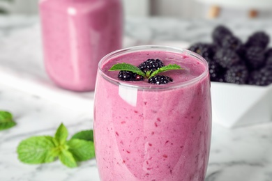 Photo of Glass of tasty blackberry smoothie on table, closeup