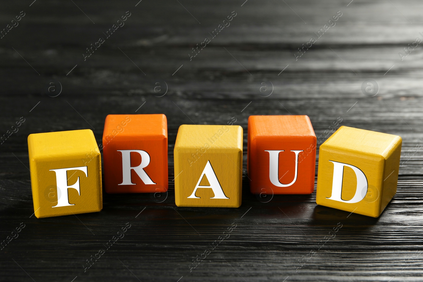 Photo of Cubes with word Fraud on black wooden background