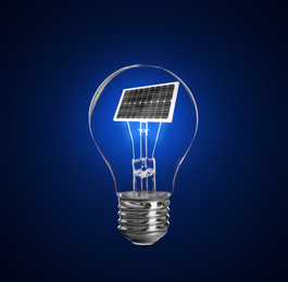 Image of Alternative energy source. Light bulb with solar panel on blue background 