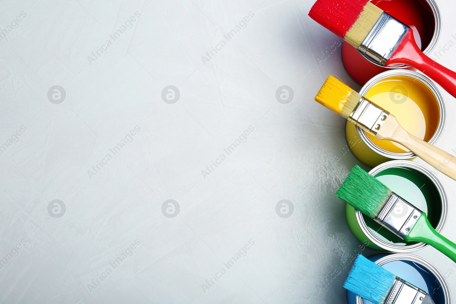 Photo of Flat lay composition with paint cans and brushes on light background. Space for text