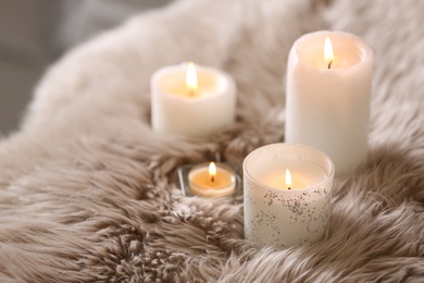 Photo of Beautiful burning candles on fuzzy faux fur rug