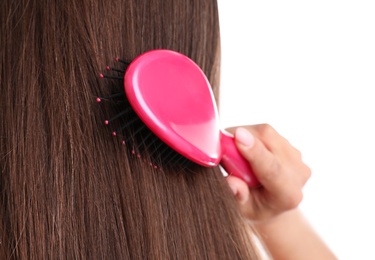 Woman with hair brush on white background, closeup