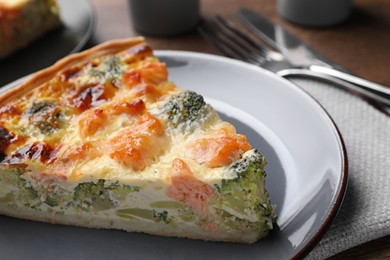 Piece of delicious homemade quiche with salmon and broccoli on plate, closeup