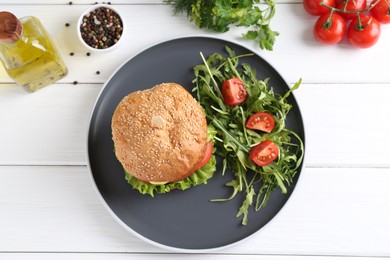 Delicious vegetarian burger served with salad on white wooden table, flat lay