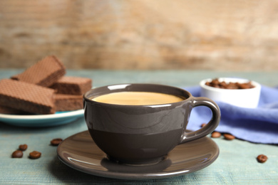 Photo of Delicious coffee and wafers for breakfast on light blue wooden table