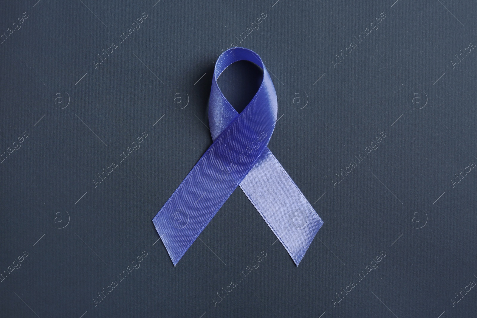 Photo of Purple awareness ribbon on black background, top view