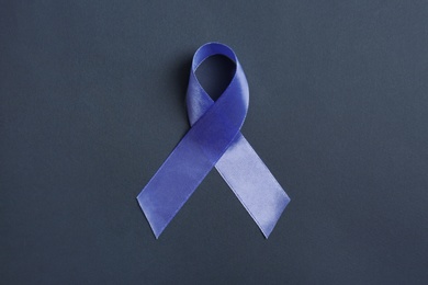 Purple awareness ribbon on black background, top view