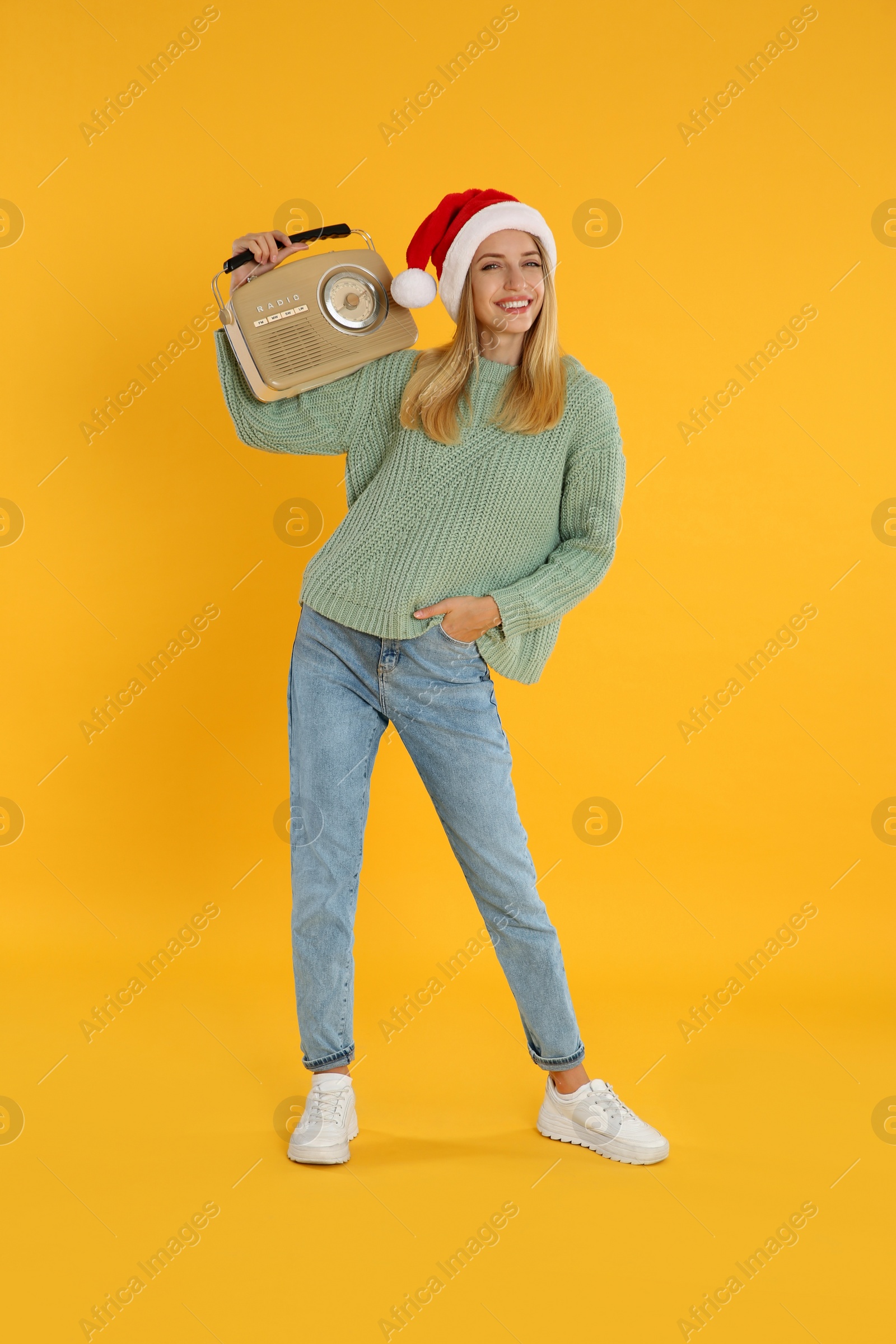 Photo of Happy woman with vintage radio on yellow background. Christmas music