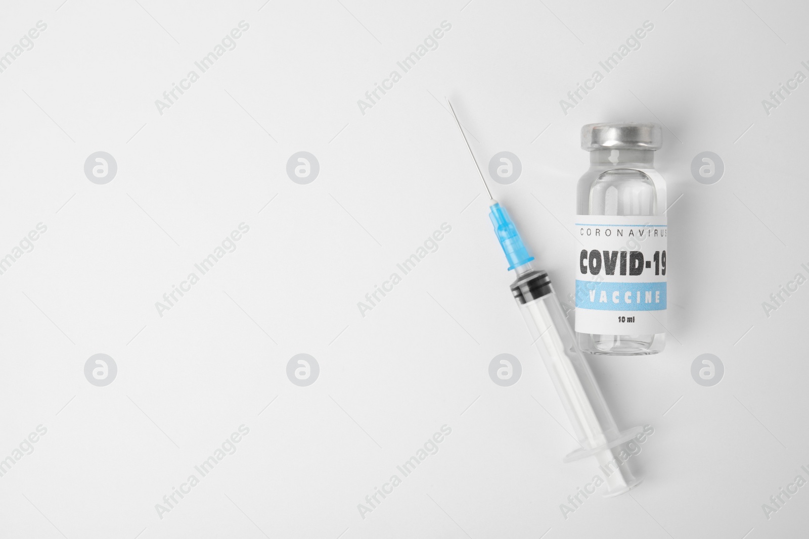 Photo of Vial with coronavirus vaccine and syringe on white background, flat lay. Space for text