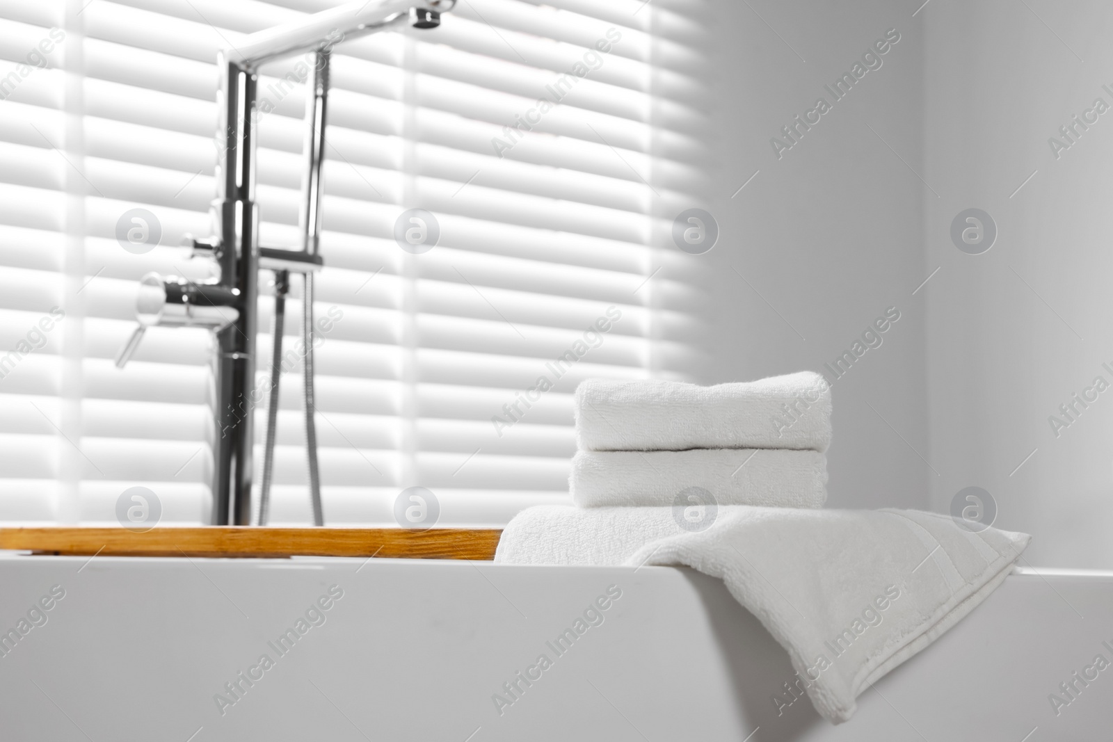 Photo of Fresh white towels on tub in bathroom. Space for text