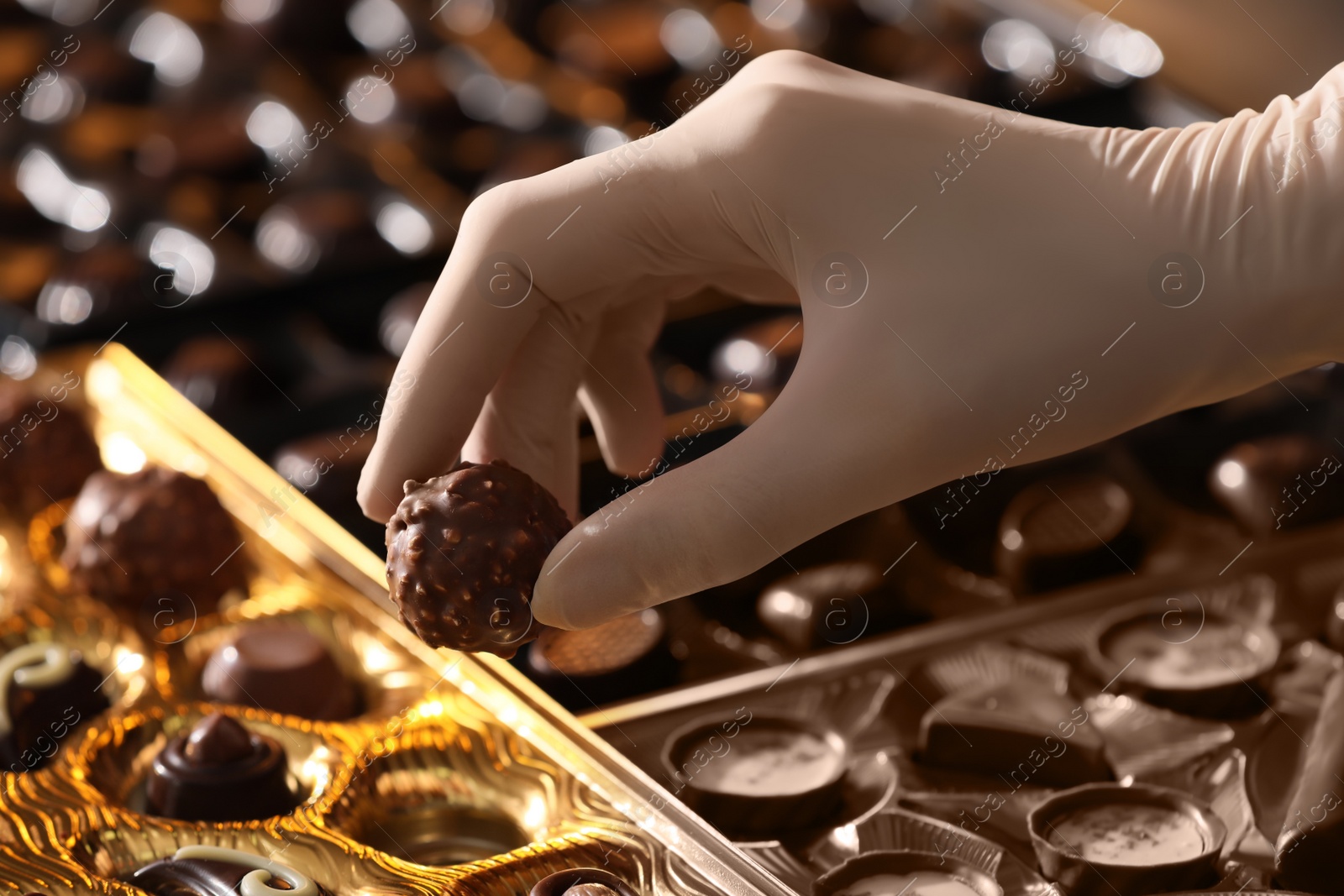 Photo of Woman packing delicious candies at production line, closeup