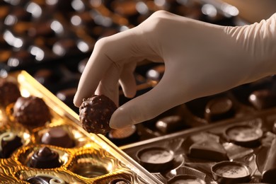 Woman packing delicious candies at production line, closeup