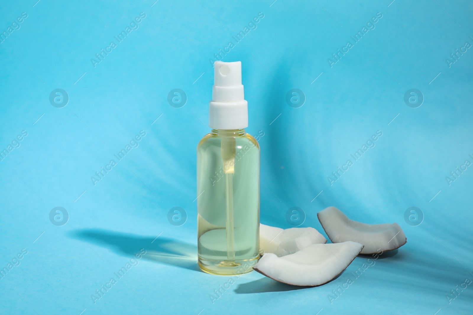 Photo of Aromatic coconut oil on light blue background