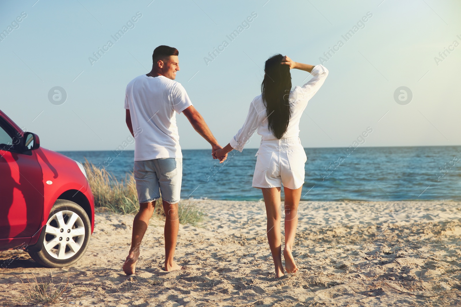 Photo of Happy couple walking on sandy beach. Summer trip