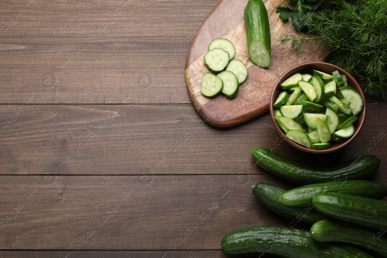 Photo of Fresh ripe cucumbers and dill on wooden table, flat lay. Space for text