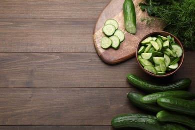 Photo of Fresh ripe cucumbers and dill on wooden table, flat lay. Space for text