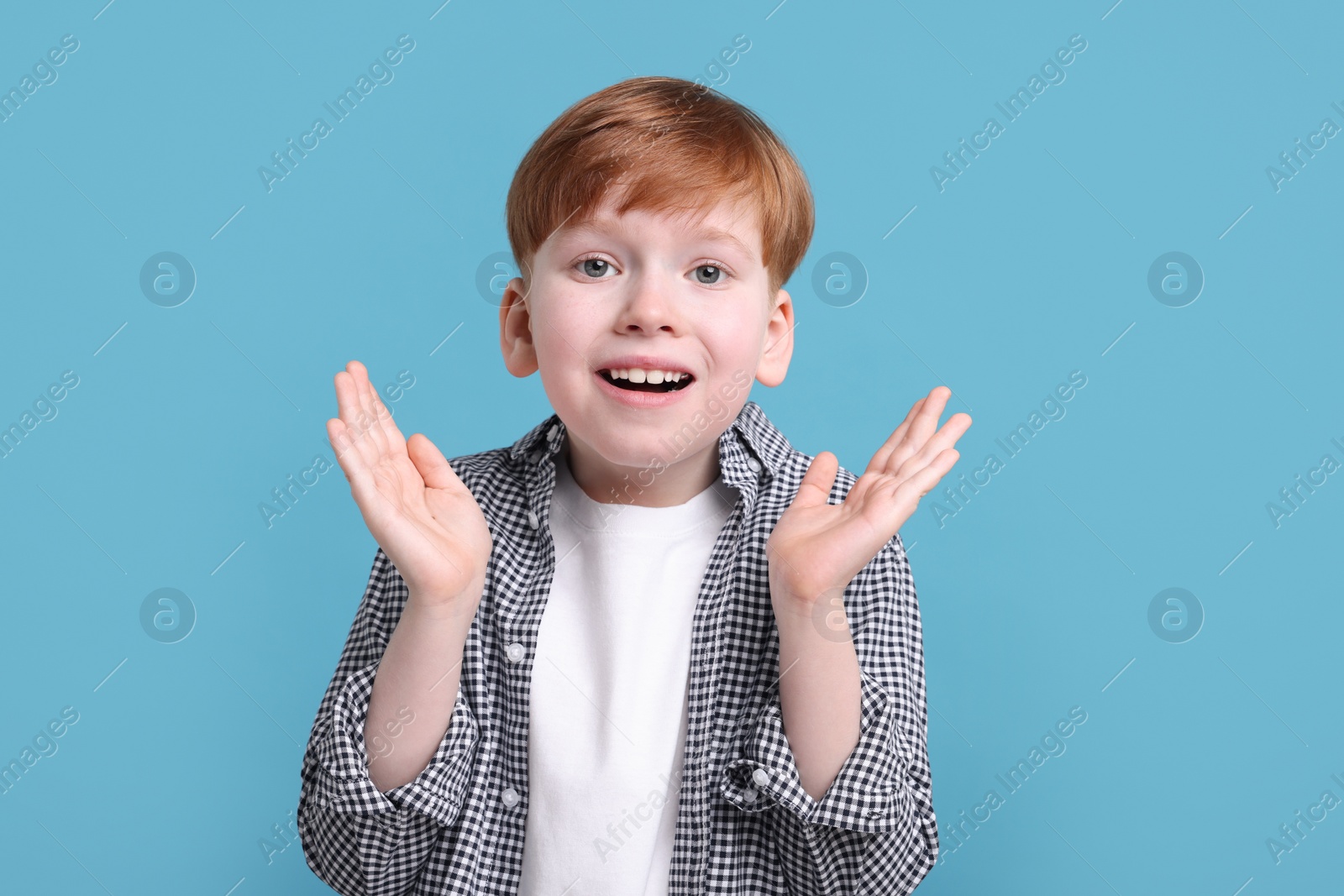 Photo of Surprised little boy on light blue background