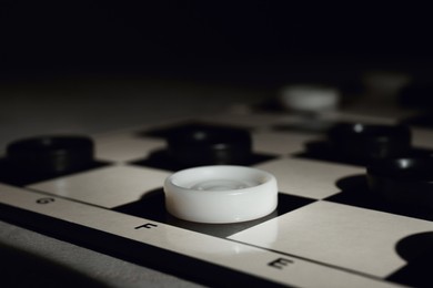 Photo of Checkerboard with game pieces on dark background, closeup