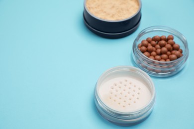 Photo of Different face powders on light blue background, space for text