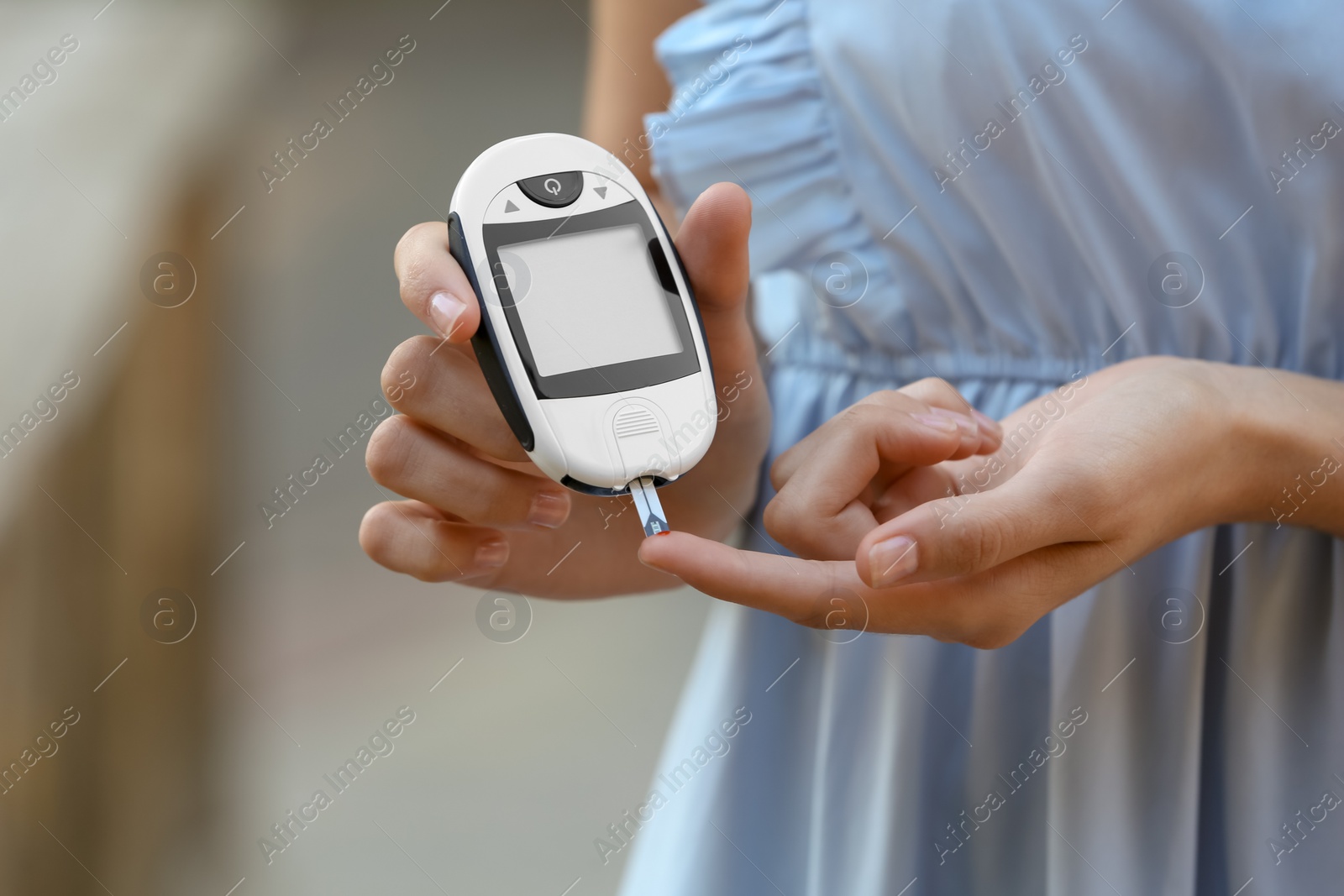 Photo of Woman using digital glucometer on blurred background. Diabetes control