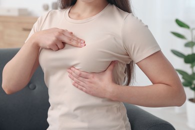 Photo of Woman doing breast self-examination at home, closeup