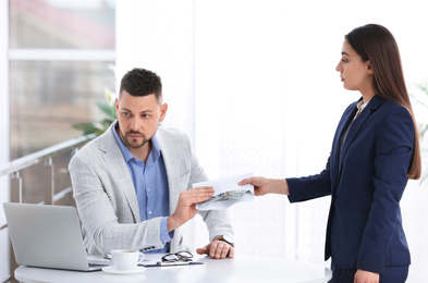 Woman giving bribe to man at table indoors