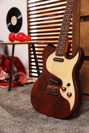 Stylish guitar and red headphones on wooden table in teenager's room