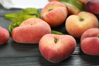 Photo of Fresh ripe donut peaches on grey wooden table, closeup