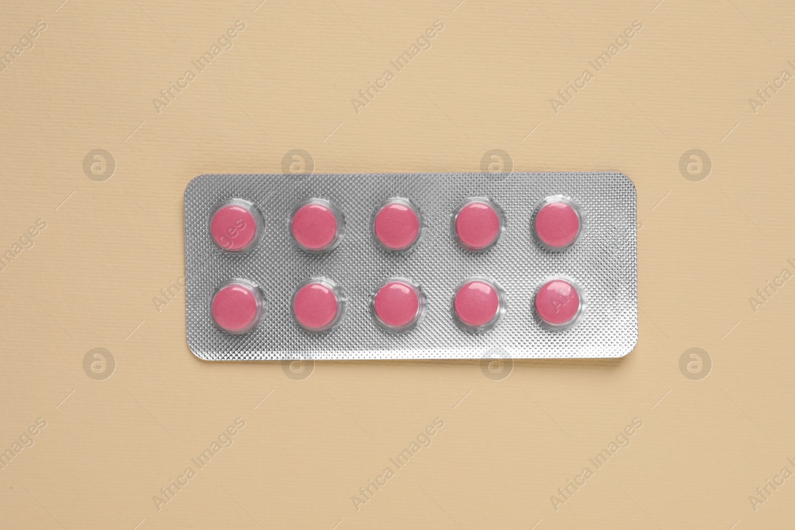 Photo of Pink pills in blister on beige background, top view