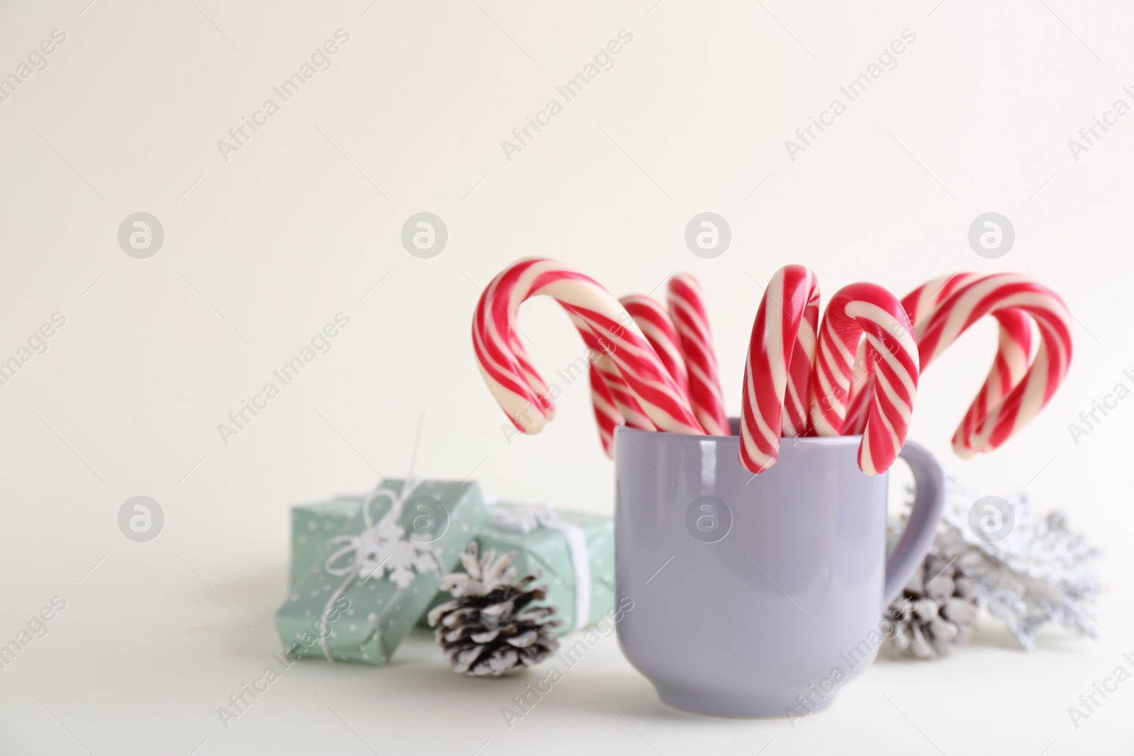 Photo of Candy canes and Christmas decor on beige background, space for text