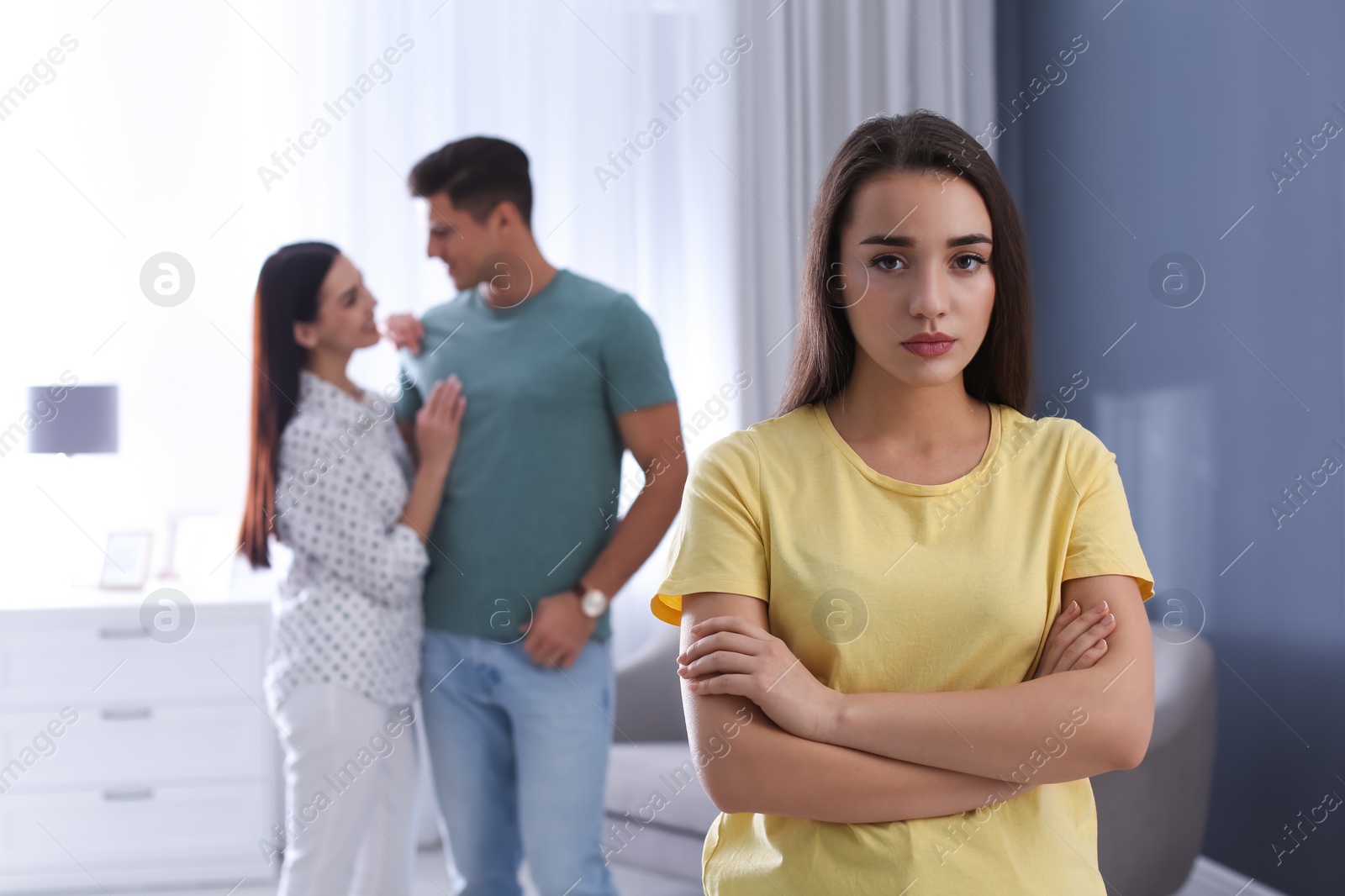 Photo of Unhappy woman feeling jealous while couple spending time together at home