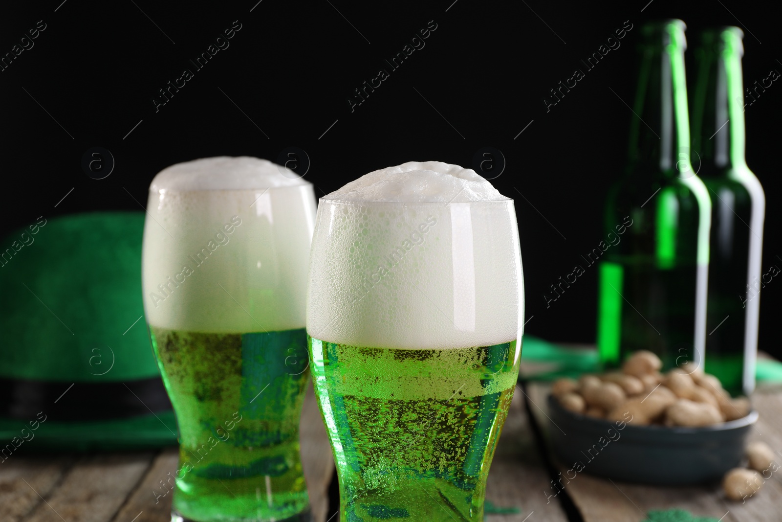 Photo of St. Patrick's day party. Green beer, leprechaun hat and nuts on wooden table, closeup