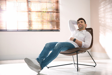 Young man relaxing near window at home. Space for text