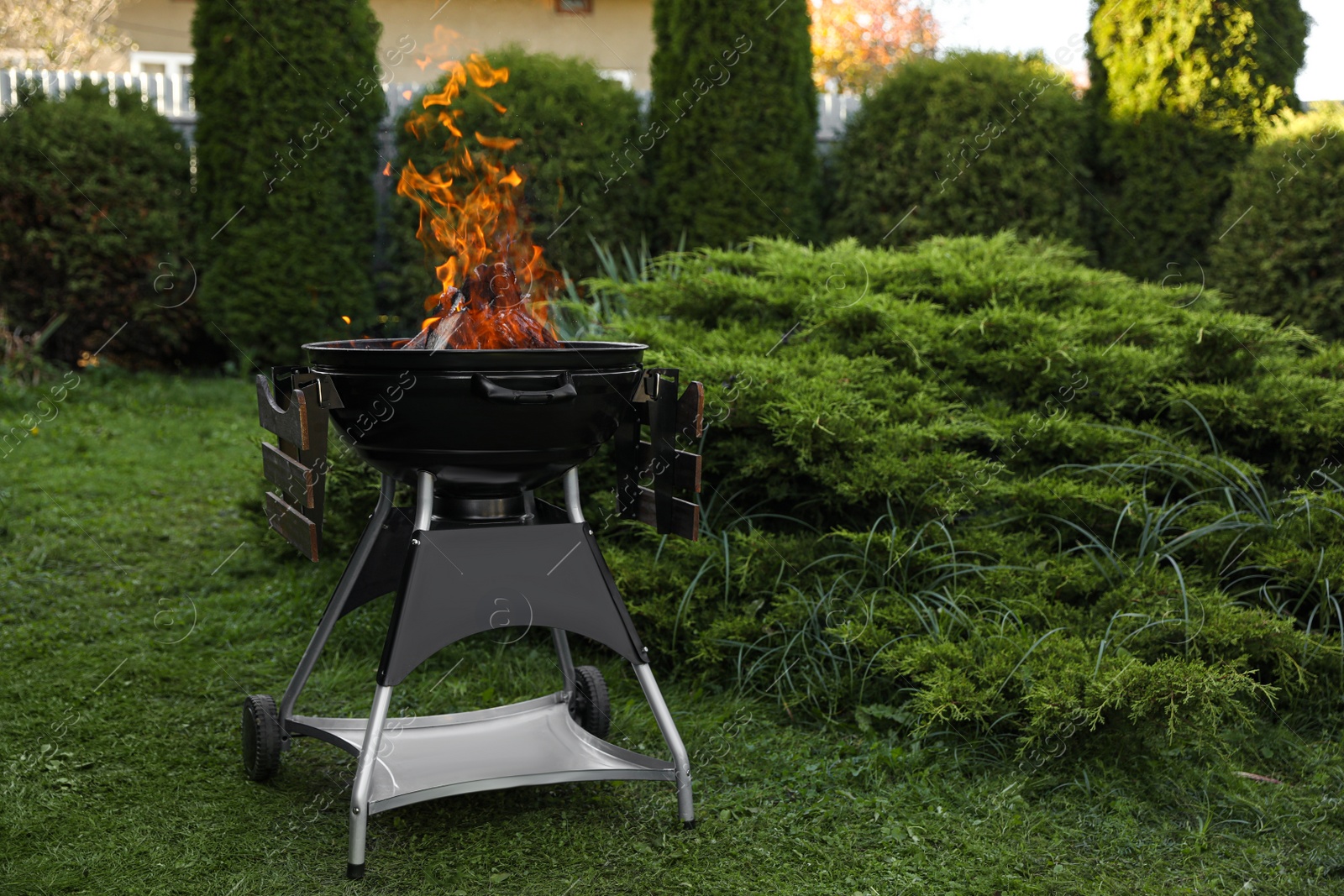 Photo of Portable barbecue grill with fire flames outdoors. Space for text