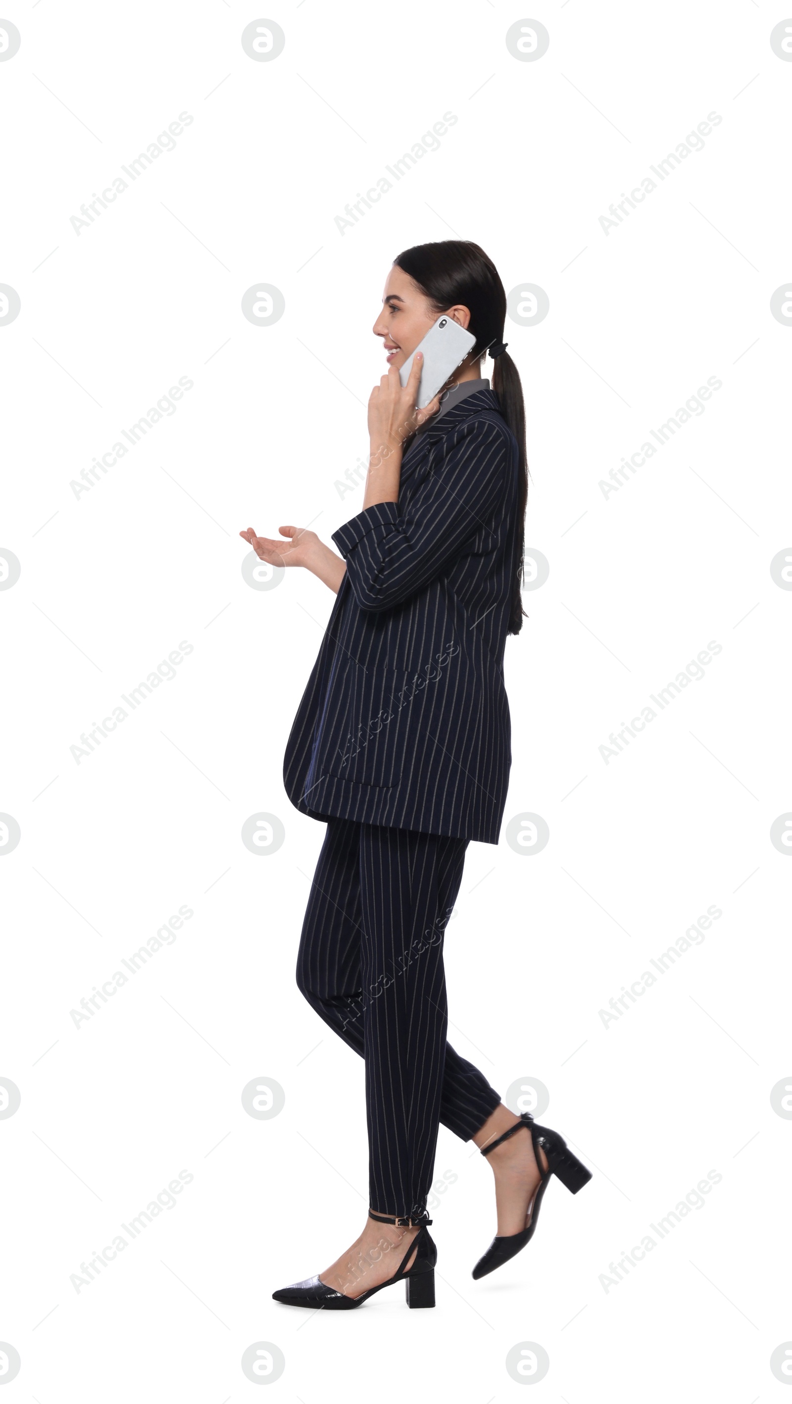 Photo of Young businesswoman talking on smartphone while walking against white background