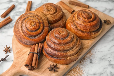 Photo of Wooden board with cinnamon rolls on table