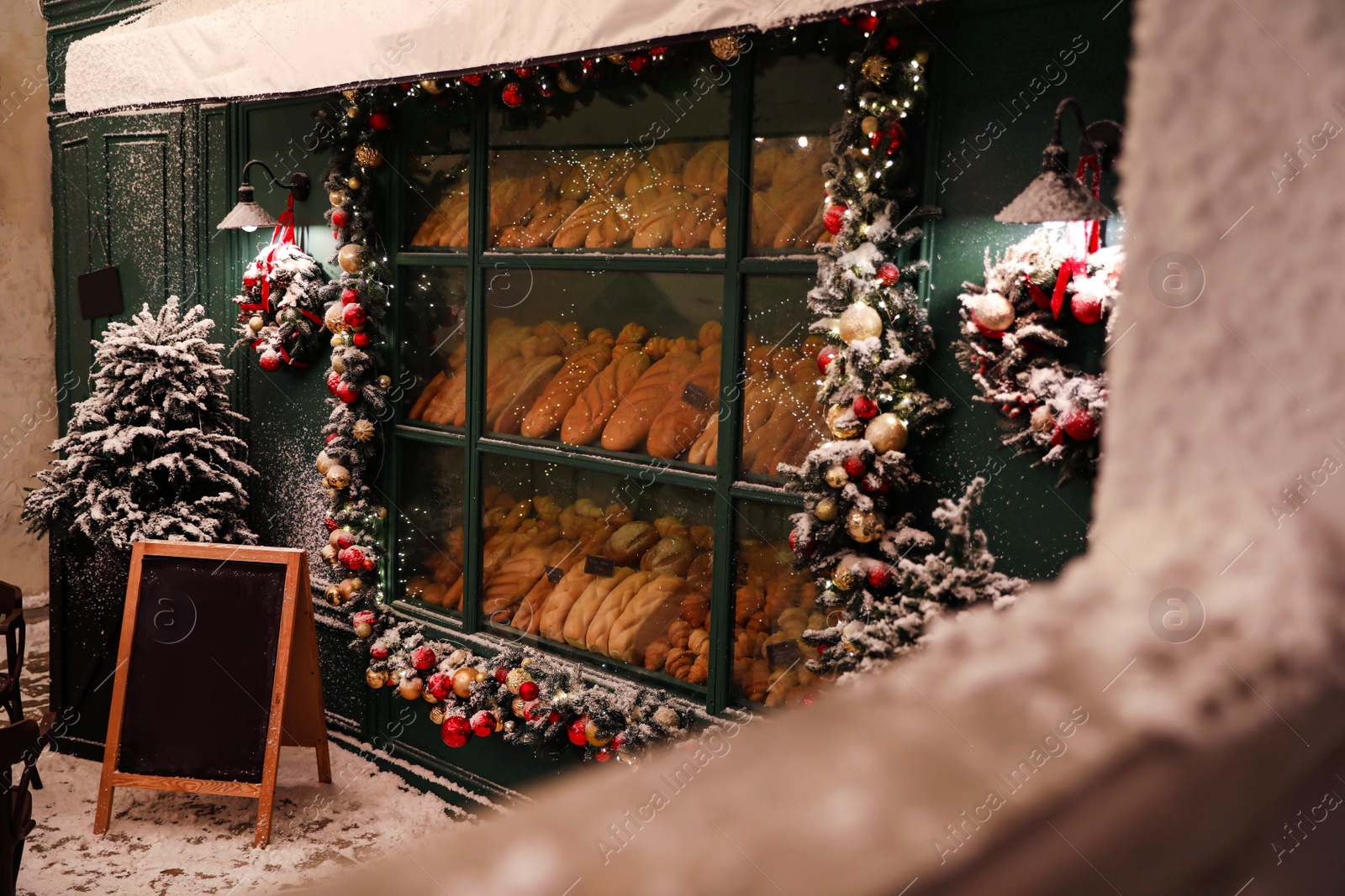 Photo of Bakery shop decorated with Christmas garland outdoors